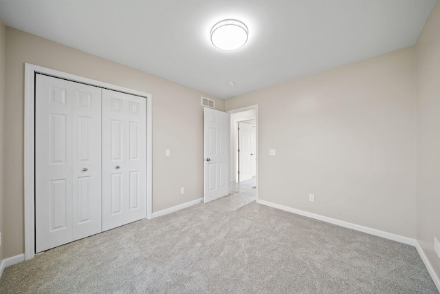 unfurnished bedroom with a closet and light colored carpet