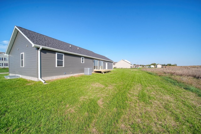 back of property with central AC and a lawn