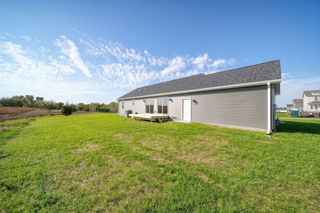 rear view of house featuring a wooden deck and a yard