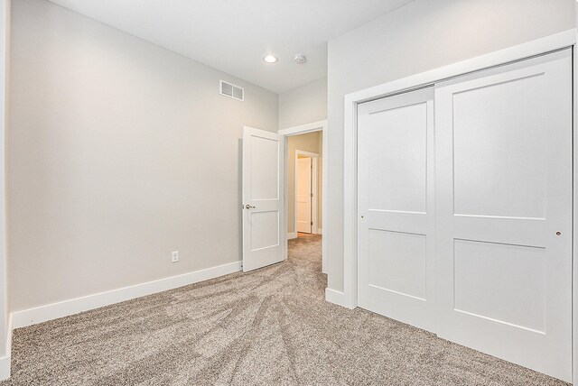 unfurnished bedroom with light carpet and a closet