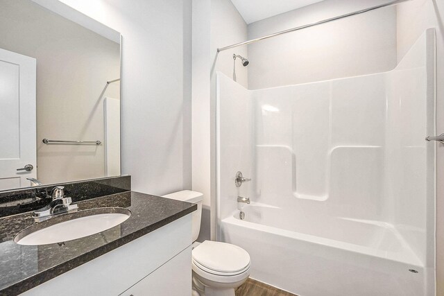 full bathroom featuring hardwood / wood-style flooring, vanity, shower / bathtub combination, and toilet