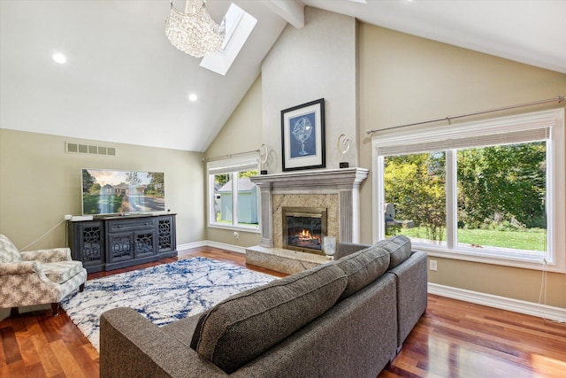 living room with a skylight, a high end fireplace, high vaulted ceiling, and hardwood / wood-style flooring