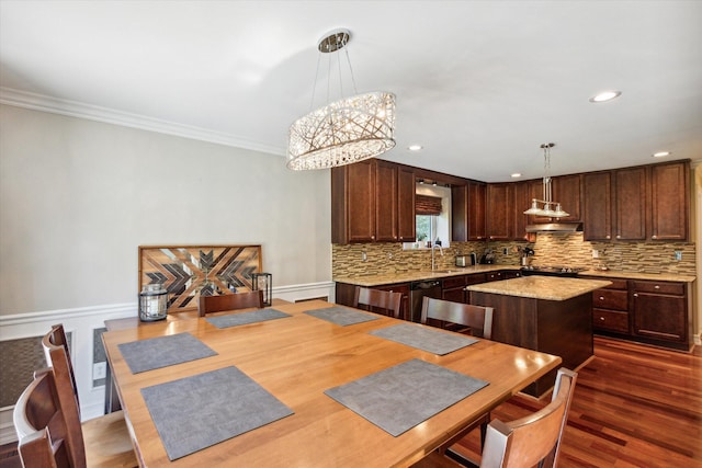 kitchen featuring ornamental molding, pendant lighting, wood-type flooring, an inviting chandelier, and a center island