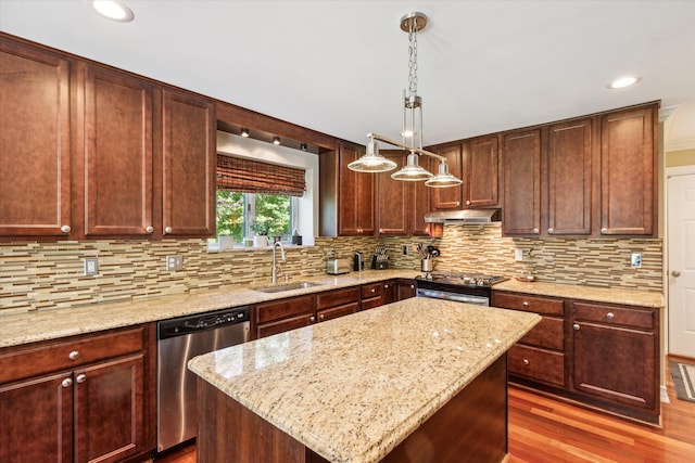 kitchen featuring sink, wood-type flooring, decorative light fixtures, a kitchen island, and appliances with stainless steel finishes