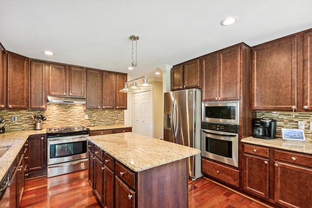 kitchen featuring light stone countertops, stainless steel appliances, decorative light fixtures, a center island, and dark hardwood / wood-style floors