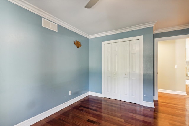 unfurnished bedroom featuring ornamental molding, a closet, ceiling fan, and dark wood-type flooring