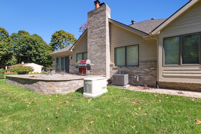 back of property with a lawn and central AC