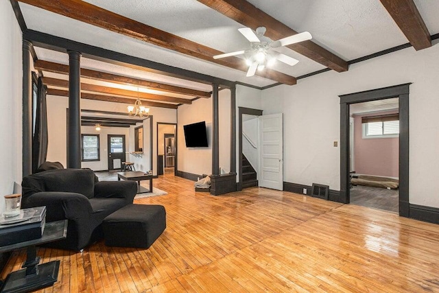 living room with beamed ceiling, light wood-type flooring, ceiling fan with notable chandelier, and a healthy amount of sunlight