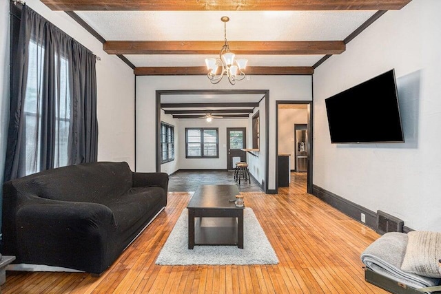 living room with beamed ceiling, wood-type flooring, and ceiling fan with notable chandelier