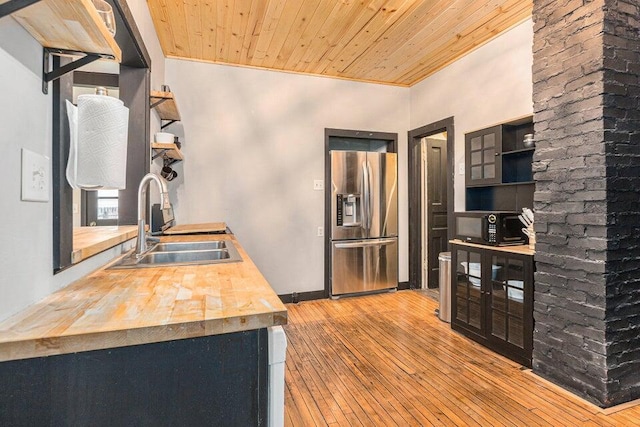 kitchen with stainless steel fridge, light hardwood / wood-style floors, wood ceiling, and sink