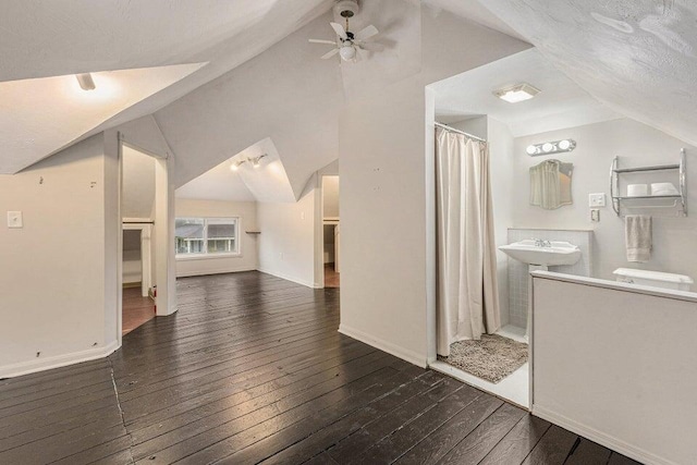 interior space with ceiling fan, sink, wood-type flooring, a textured ceiling, and lofted ceiling