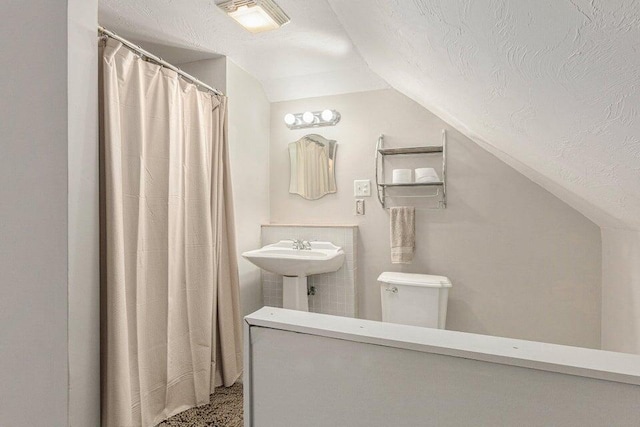 bathroom with a textured ceiling, sink, lofted ceiling, and toilet