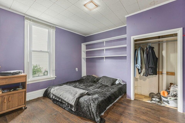 bedroom with multiple windows, a closet, dark hardwood / wood-style flooring, and ornamental molding