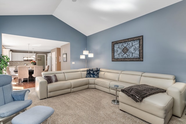 carpeted living room featuring a chandelier and lofted ceiling