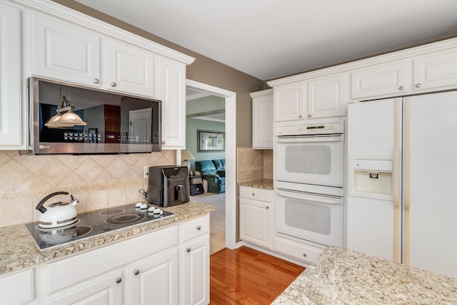 kitchen with decorative backsplash, white appliances, light hardwood / wood-style flooring, and white cabinetry