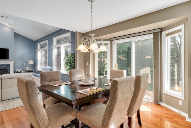 dining room with vaulted ceiling, light hardwood / wood-style flooring, and ceiling fan with notable chandelier