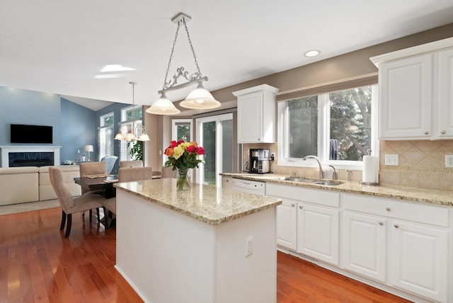 kitchen featuring wood-type flooring, pendant lighting, white cabinets, and sink