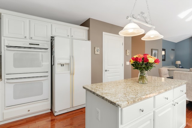 kitchen with white appliances, white cabinetry, light hardwood / wood-style floors, a kitchen island, and hanging light fixtures