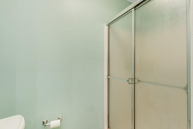 bathroom featuring toilet and a shower with shower door