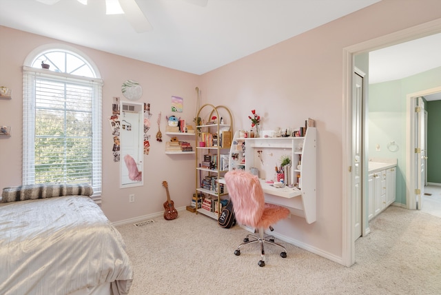 bedroom with light colored carpet, ensuite bath, and ceiling fan