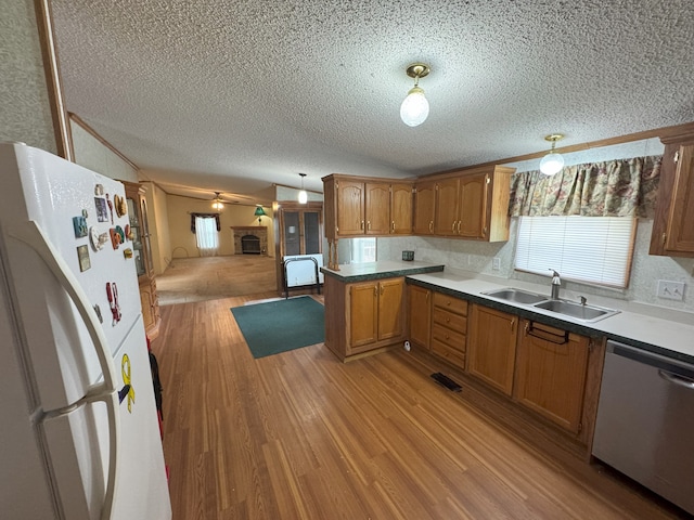 kitchen featuring sink, stainless steel dishwasher, light wood-type flooring, decorative light fixtures, and white fridge