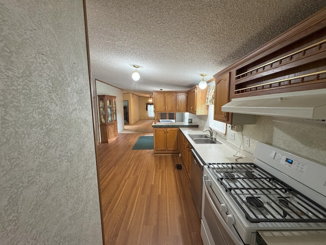 kitchen featuring a textured ceiling, light hardwood / wood-style floors, sink, and gas range