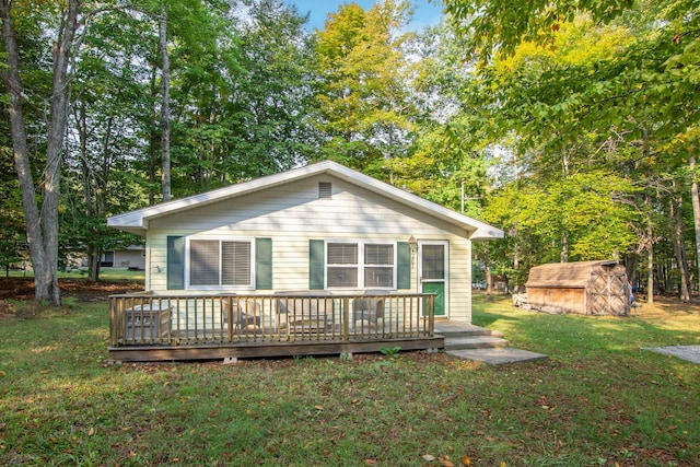 back of house with a yard, a deck, and a storage unit