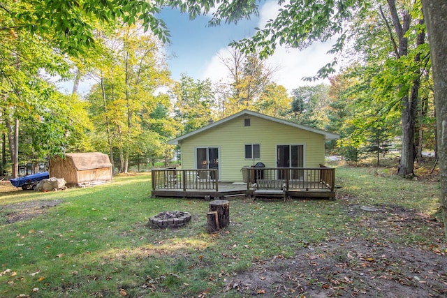 back of house with a storage shed, a yard, a fire pit, and a deck