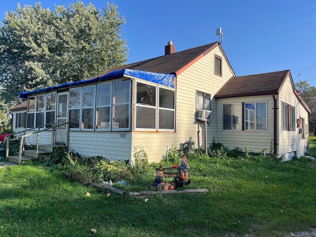 back of house with a lawn, a sunroom, and cooling unit