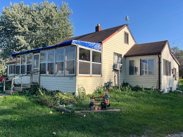 back of house with a lawn, a sunroom, and cooling unit