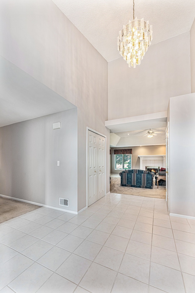 interior space with light tile patterned flooring, a high ceiling, a textured ceiling, and an inviting chandelier