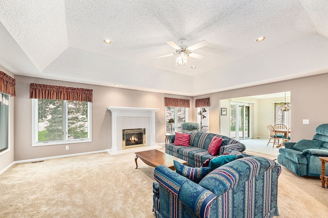 living room with a textured ceiling, ceiling fan, light carpet, and a tiled fireplace