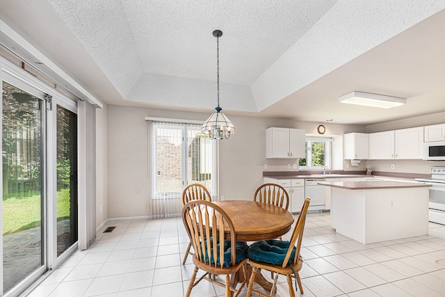 dining space featuring a tray ceiling, light tile patterned floors, a textured ceiling, and an inviting chandelier