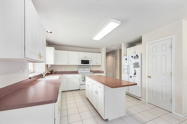 kitchen with white appliances, a center island, and white cabinets