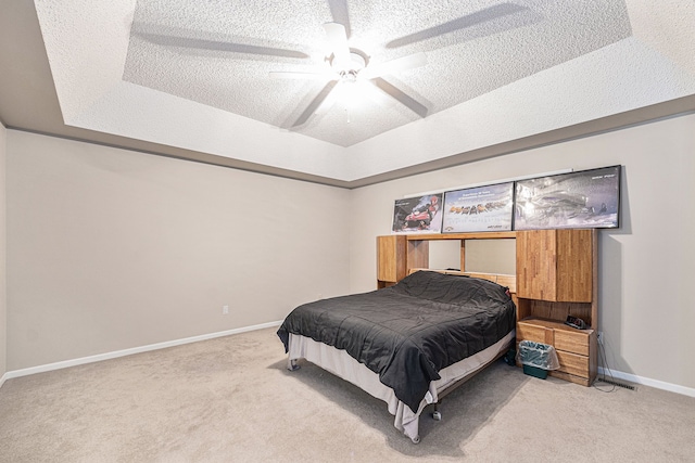 bedroom featuring light carpet, a textured ceiling, a raised ceiling, and ceiling fan