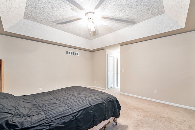 bedroom with carpet flooring, ceiling fan, a textured ceiling, and a tray ceiling