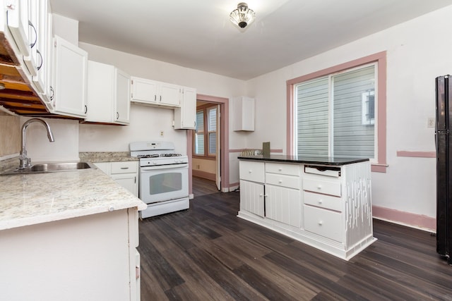 kitchen with white gas stove, white cabinets, dark wood-type flooring, and sink