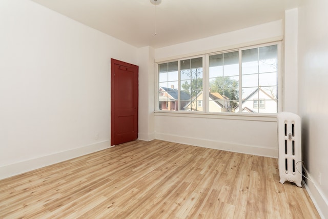 spare room featuring light wood-type flooring and radiator