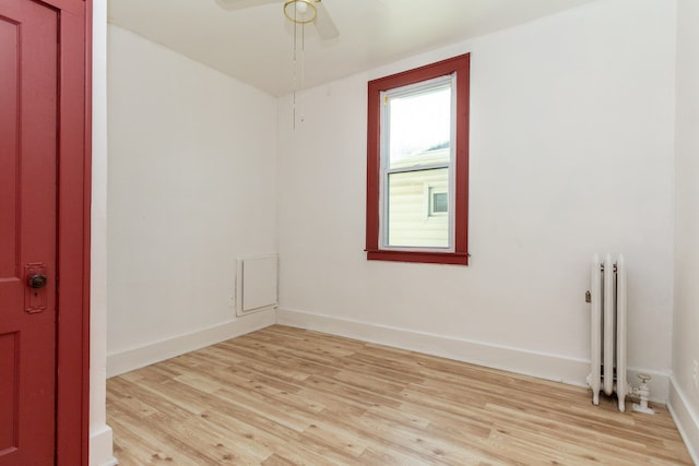 unfurnished room featuring radiator heating unit, light hardwood / wood-style floors, and ceiling fan