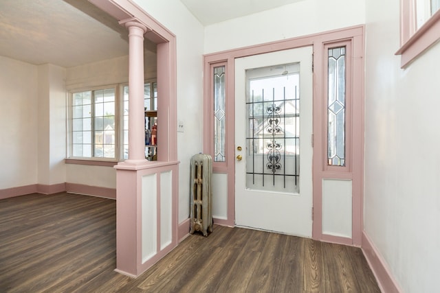 foyer entrance featuring ornate columns, dark hardwood / wood-style flooring, and radiator heating unit