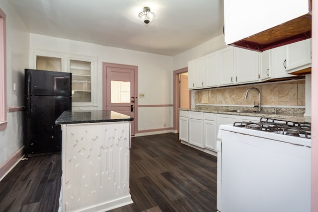 kitchen featuring white gas range, white cabinetry, black refrigerator, and stone countertops