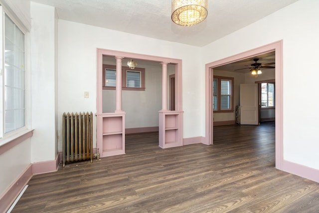 unfurnished room with a textured ceiling, radiator heating unit, ceiling fan with notable chandelier, and dark hardwood / wood-style floors