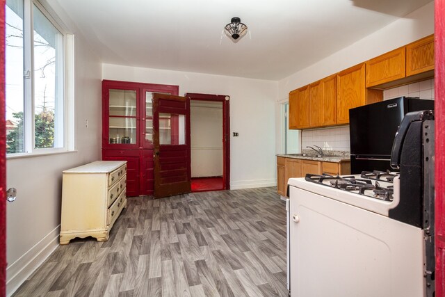 11434 Mcdougall St, Hamtramck, MI 48212 - kitchen featuring white gas range oven, baseboards, refrigerator, brown cabinets, and light wood finished floors