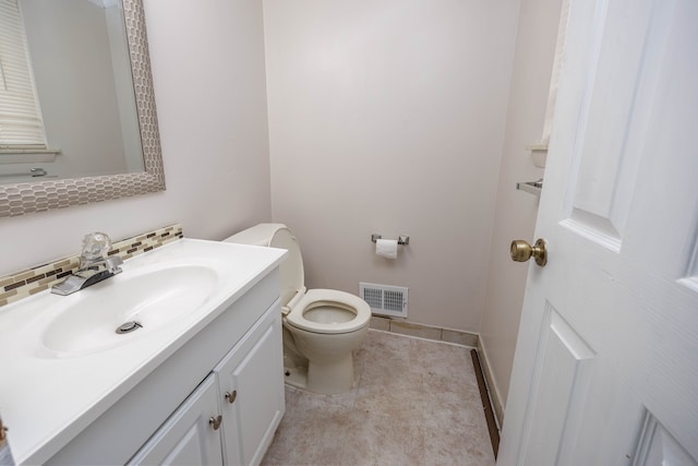 bathroom with tile patterned flooring, decorative backsplash, vanity, and toilet