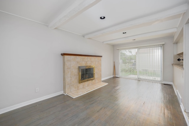 unfurnished living room featuring dark hardwood / wood-style floors, beam ceiling, and a tiled fireplace