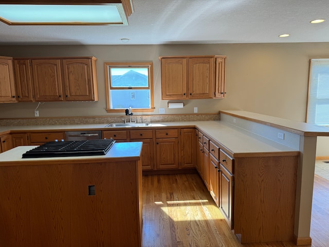 kitchen with a center island, sink, stainless steel dishwasher, light wood-type flooring, and kitchen peninsula