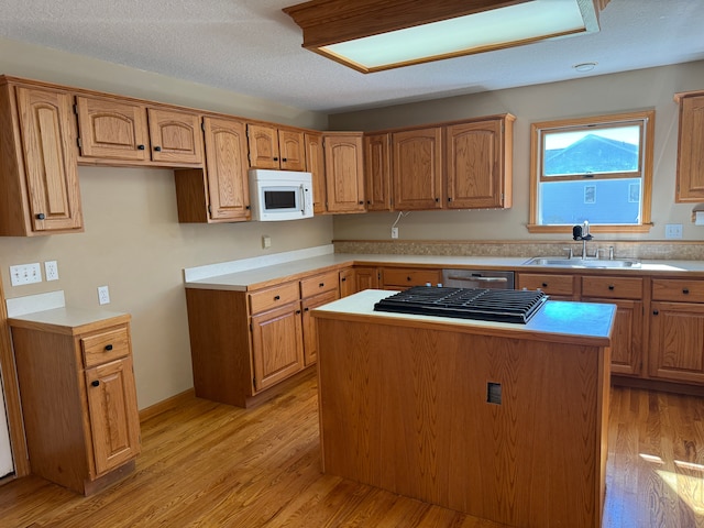 kitchen featuring light hardwood / wood-style flooring, a kitchen island, a textured ceiling, and sink