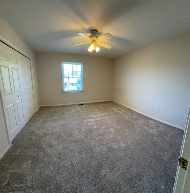 unfurnished bedroom with dark colored carpet, ceiling fan, and a closet