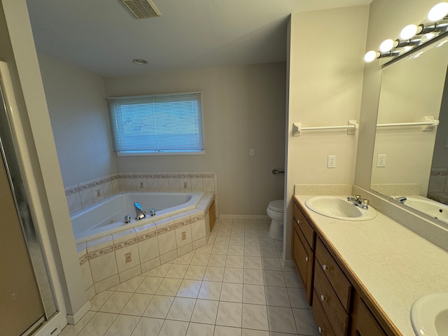 bathroom with tile patterned flooring, a relaxing tiled tub, toilet, and vanity