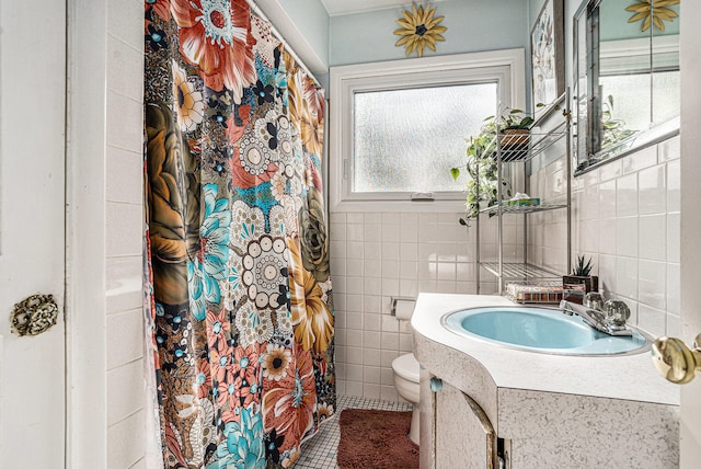 bathroom with tile patterned flooring, vanity, toilet, and tile walls